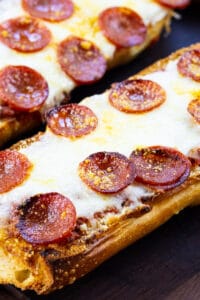 Two Pieces of Pepperoni French Bread Pizza on a cutting board.
