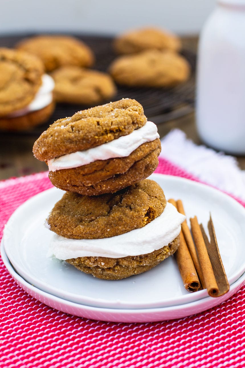 Two Chewy Gingerbread Sandwich Cookies on small plate with cinnamon sticks.