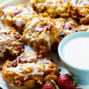 Glazed Strawberry Fritters on a plate with bowl of glaze.