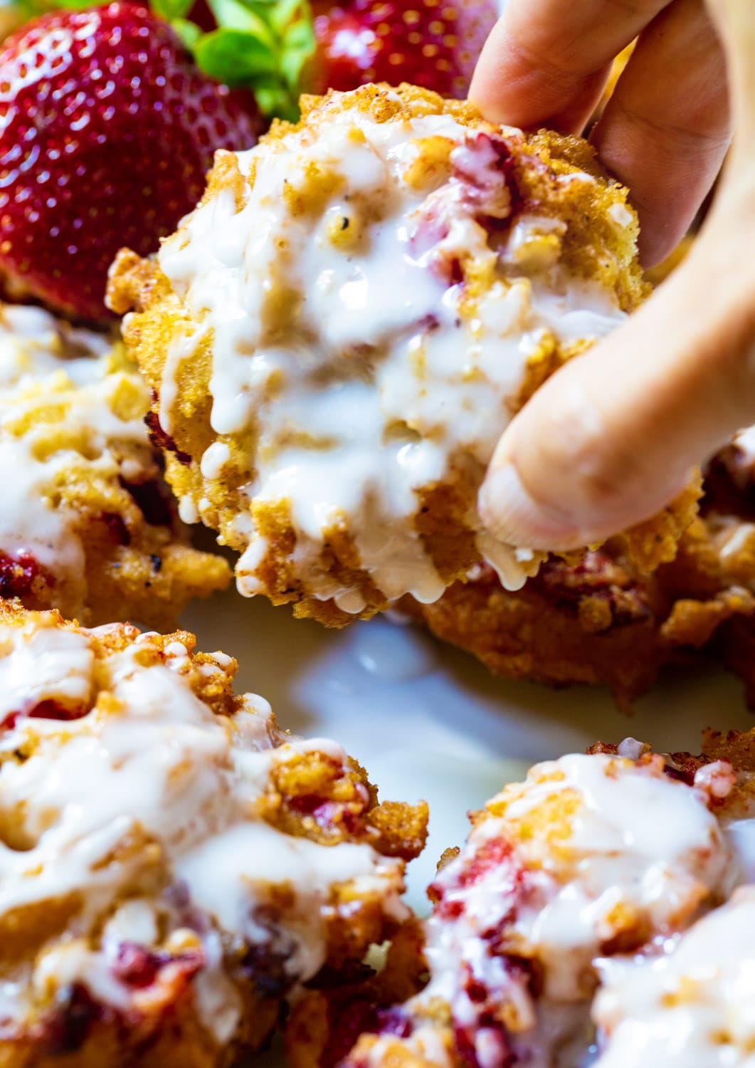 Hand picking up Glazed Strawberry Fritter.