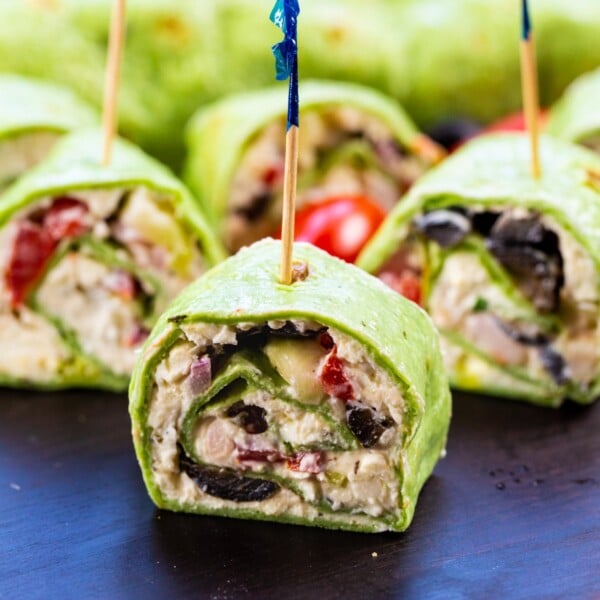 Greek Salad Pinwheels on wooden cutting board.