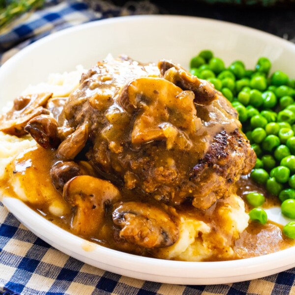 Hamburger Steak over mashed potatoes with peas.