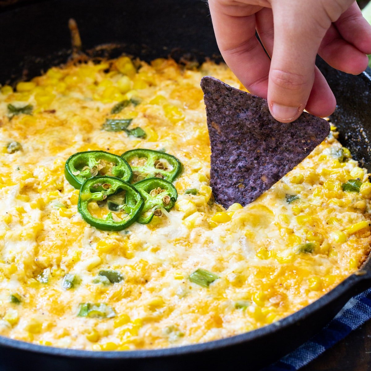 Chip scooping up Hot Corn Dip with Jalapenos.