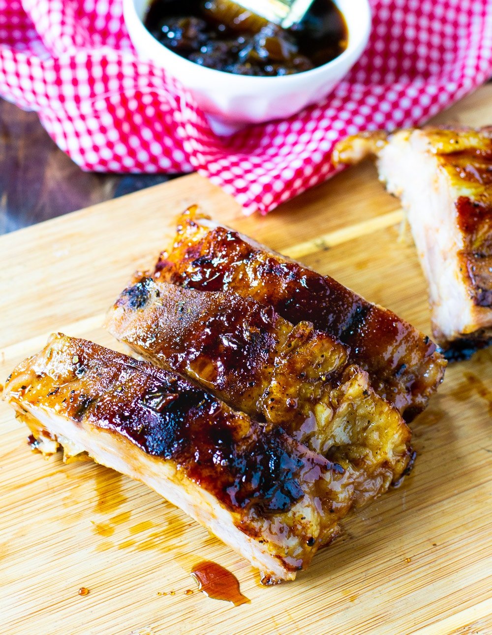 Ribs on a cutting board with bowl of sauce.