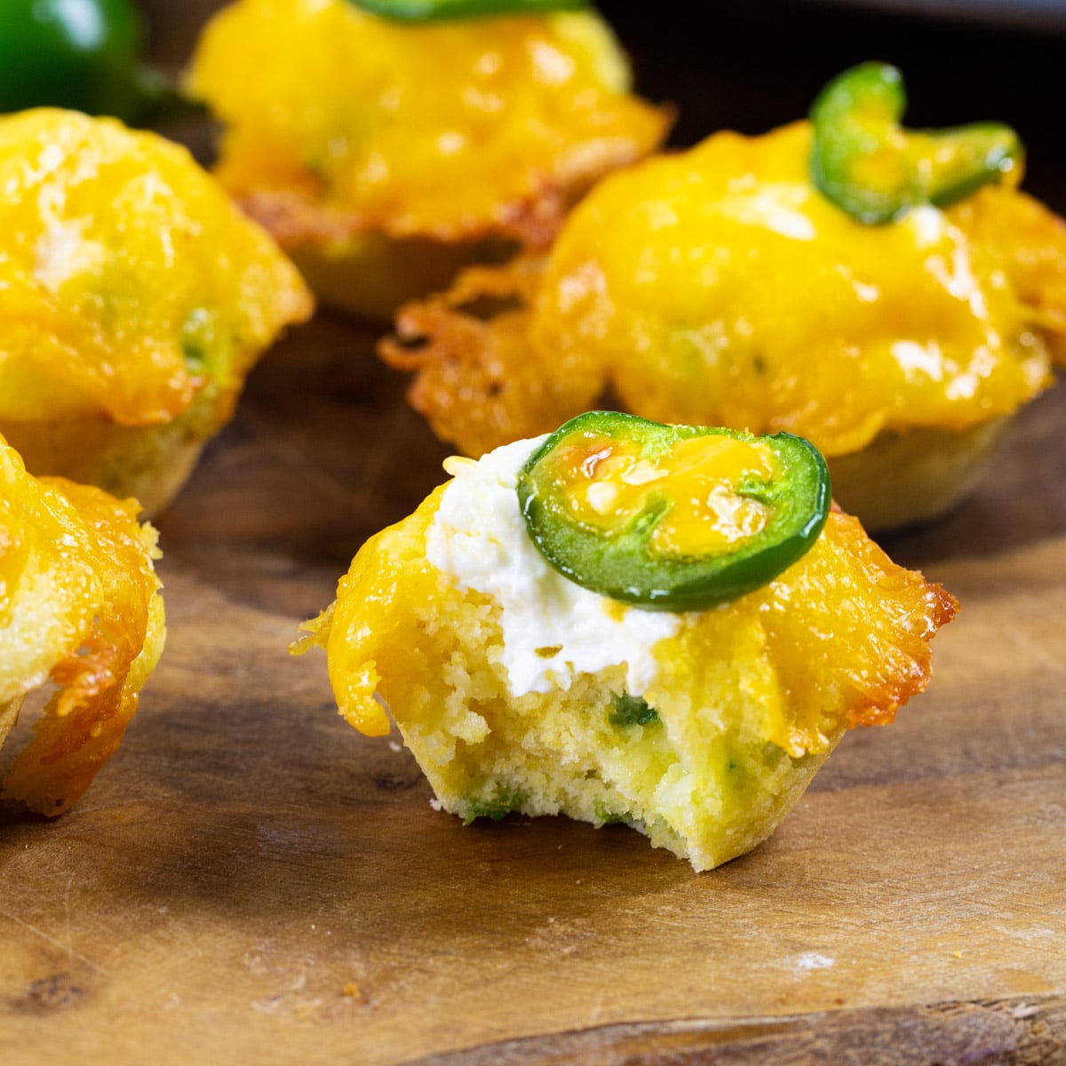Jalapeno Popper Corn Muffins with bite taken out of one to show inside.