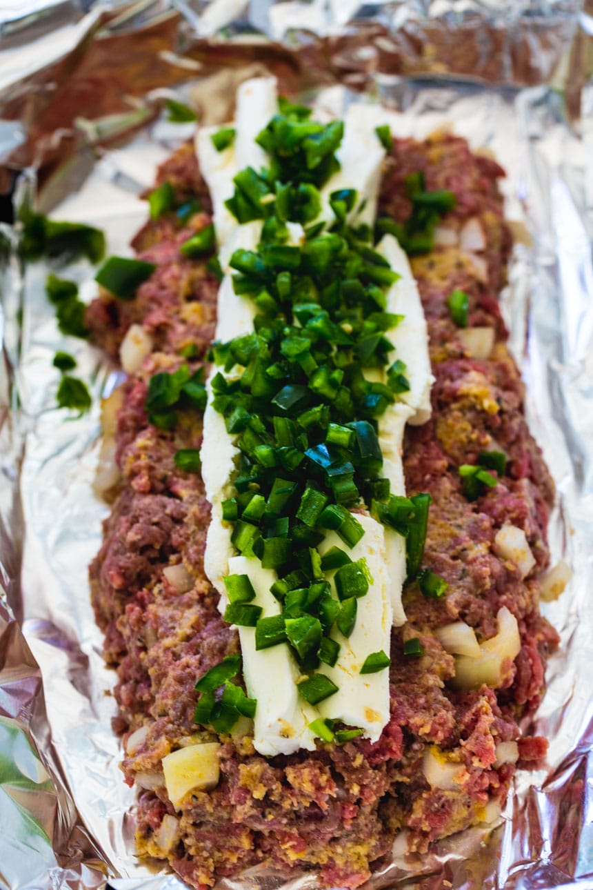 Meatloaf mixture with cream cheese and jalapenos on top.