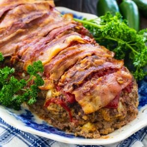 Meatloaf wrapped in bacon on a serving platter with parsley