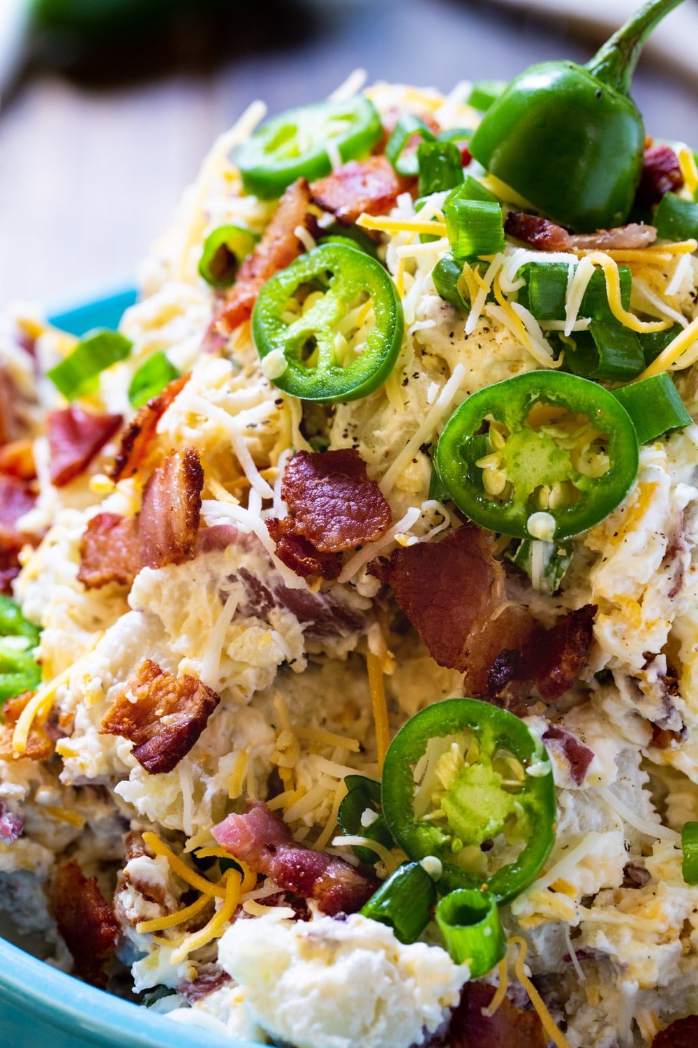 Close-up of potato salad covered with jalapeno slices and crumbled bacon.