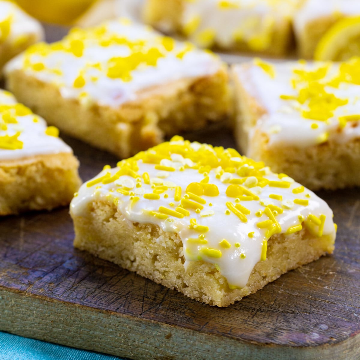 Lemon Cookie Bars topped with yellow sprinkles on a wood cutting board.