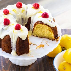 Lemon Pound Cake topped with raspberries on a cake stand.