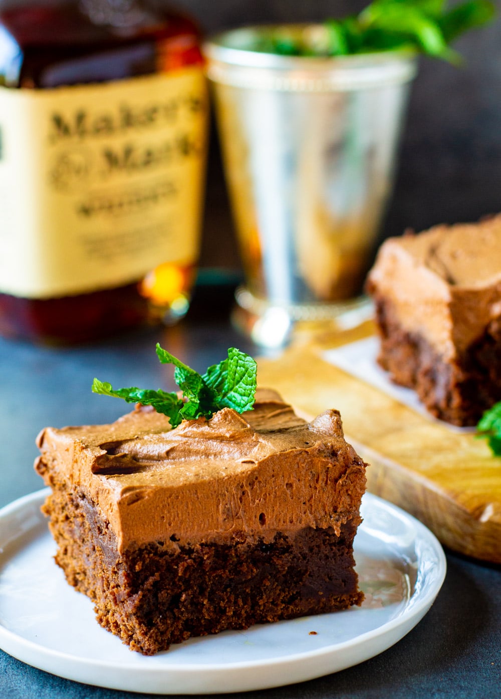 Mint Julep Brownie on small white plate with bottle of bourbon in background.