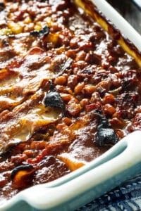 Molasses Baked Beans topped with bacon in a baking dish.