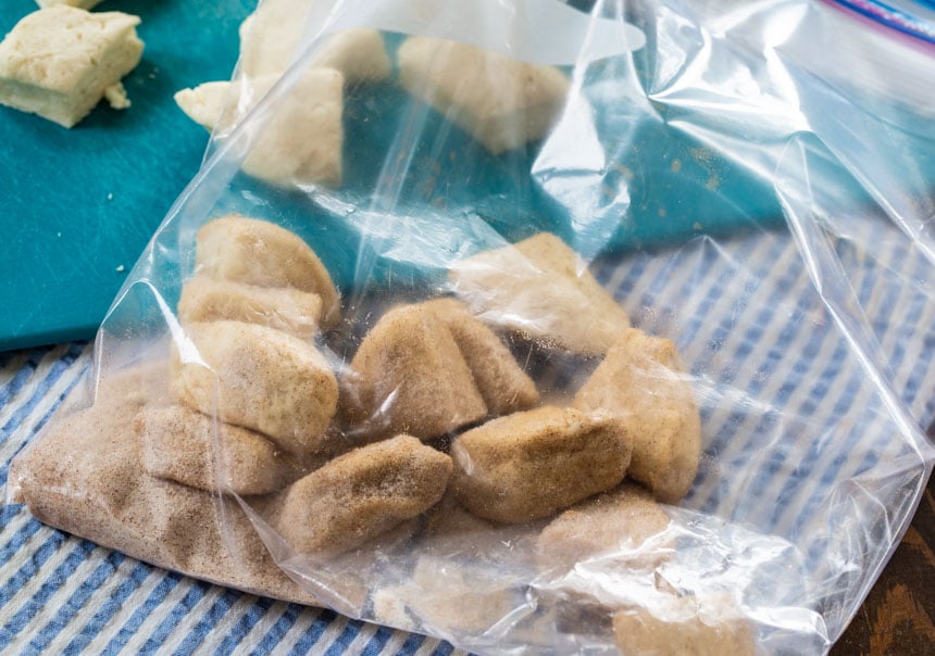 Biscuit pieces in plastic bag with cinnamon-sugar mixture.