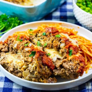 Two slices of Mozzarella Stuffed Meatloaf on plate with pasta.