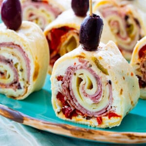 Muffaletta Pinwheels topped with black olives on a plate.