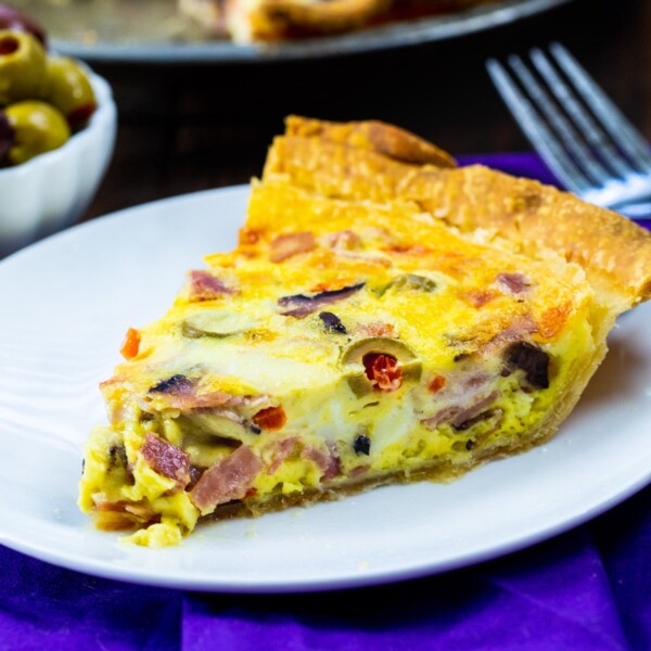 Slice of Muffaletta Quiche on a white plate.