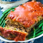 Meatloaf on serving plate with green beans.