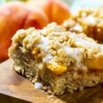 Peach Cobbler Bars with fresh peaches in background.