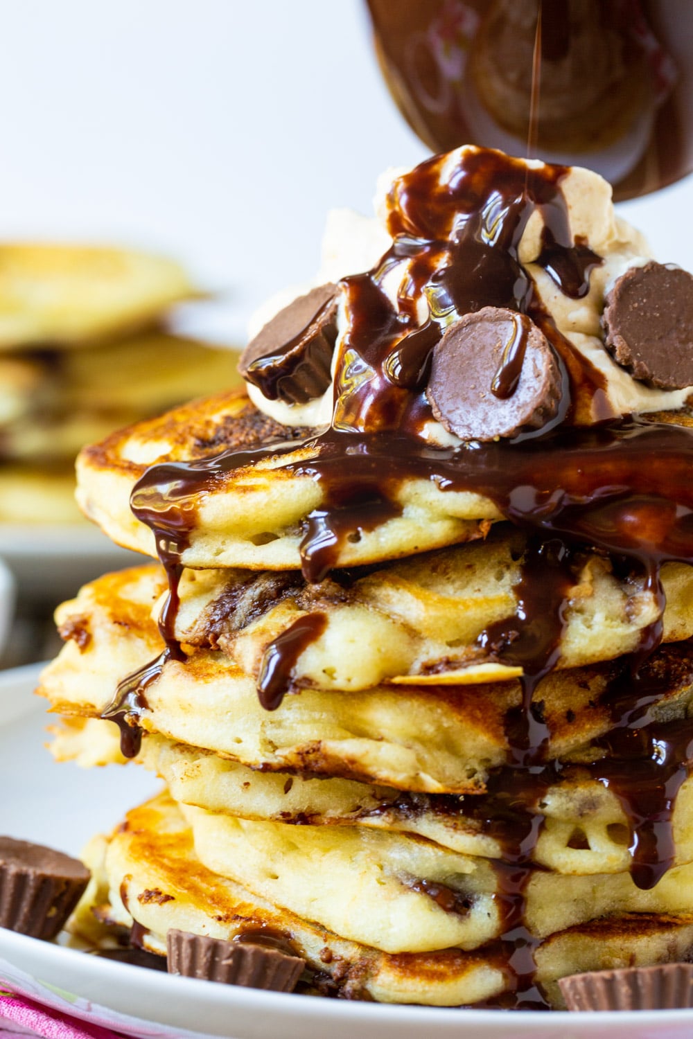 Chocolate syrup drizzling down stack of pancakes.