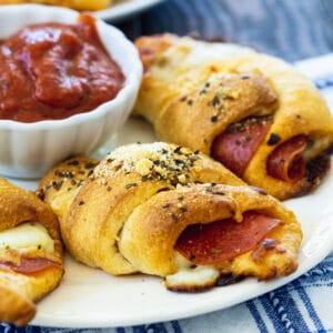 Pepperoni Crescent Rolls on a plate with bowl of marinara.