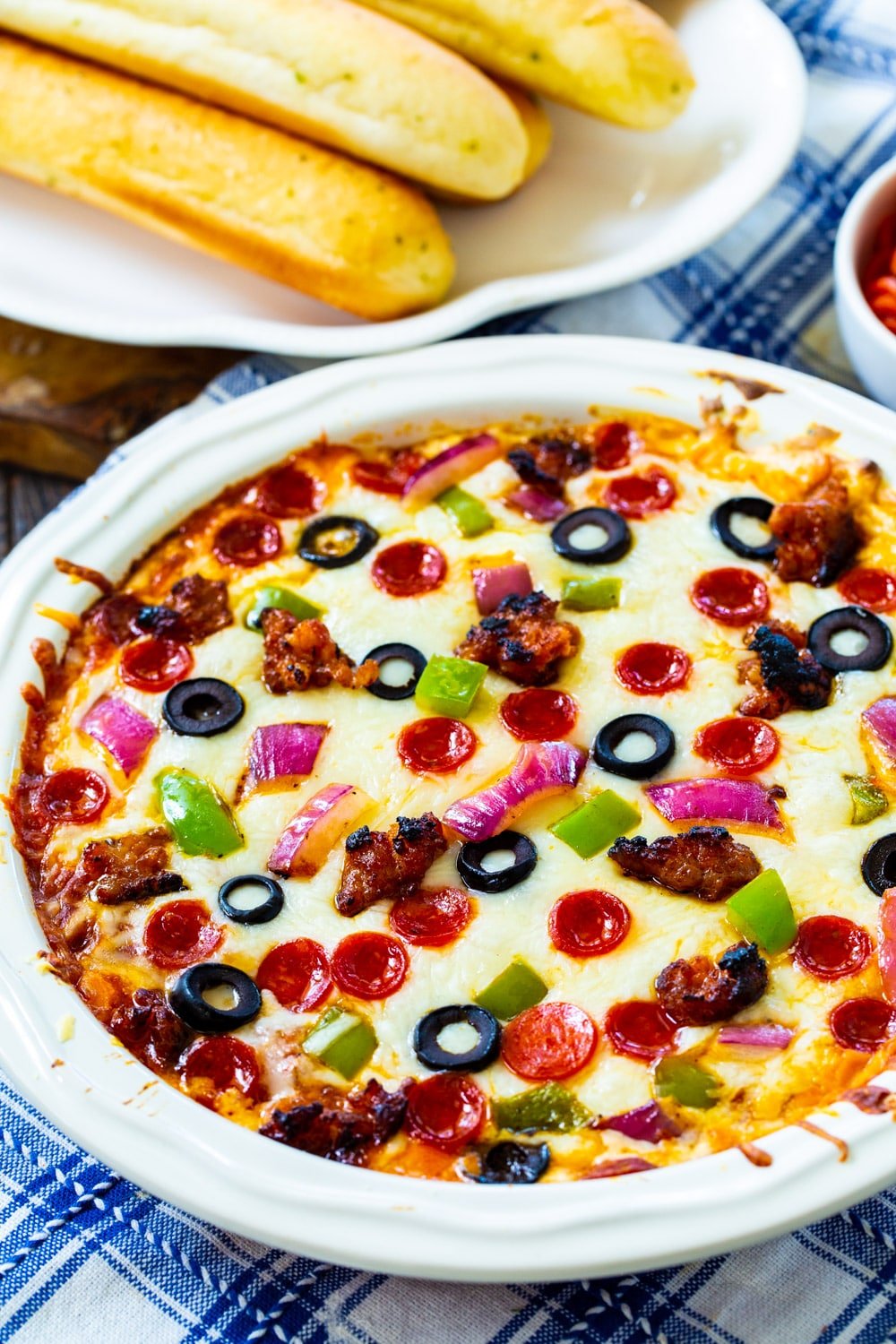 Supreme Pizza Dip with plate of bread sticks.