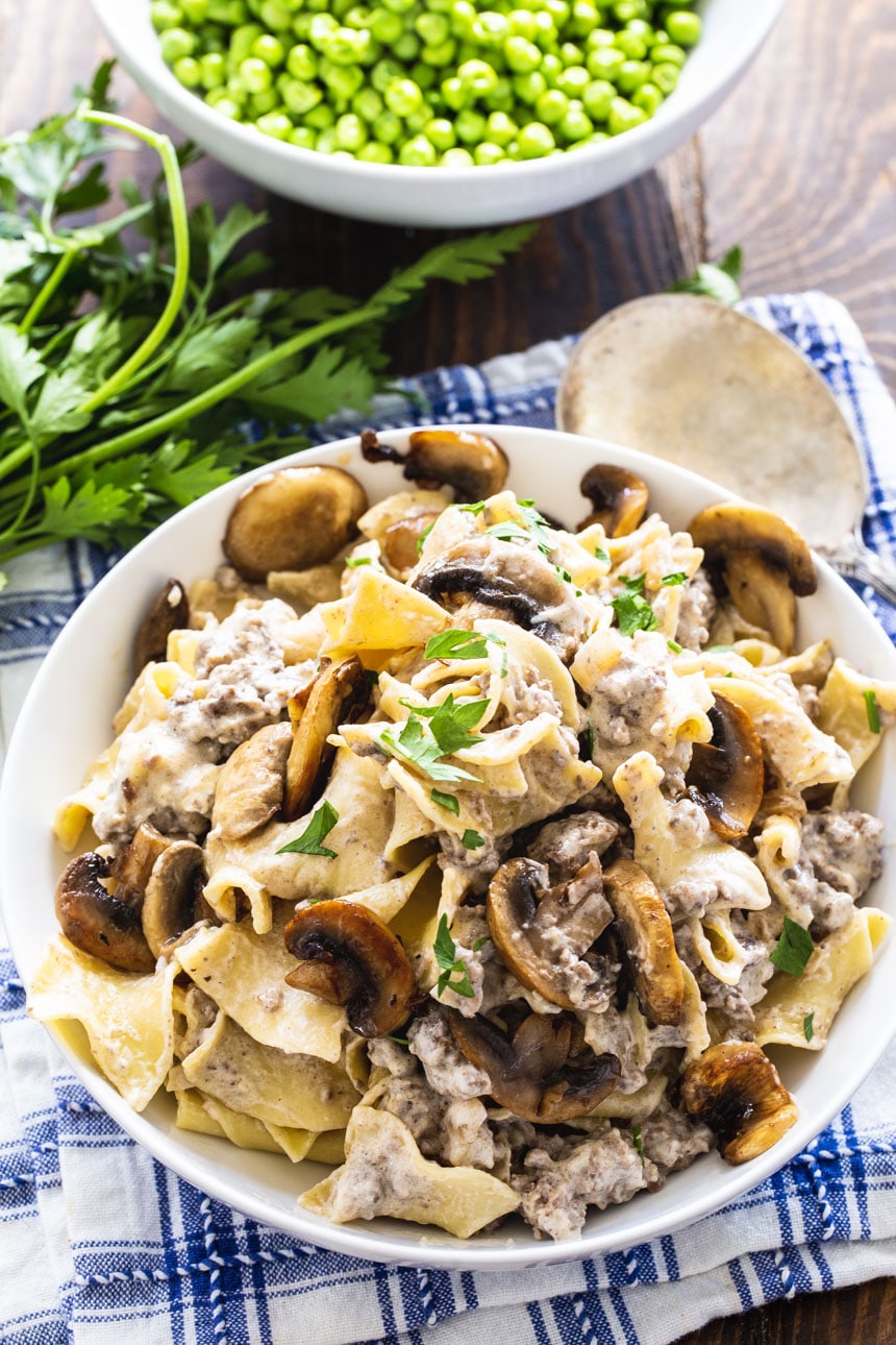 Bowl full of Beef Stroganoff and a bowl full of peas