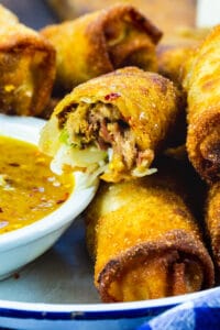 Pulled Pork Egg Rolls in serving tray with peach dipping sauce.