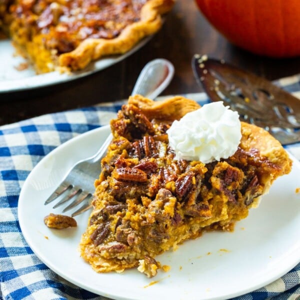 Slice of pie on a white plate with whipped cream.