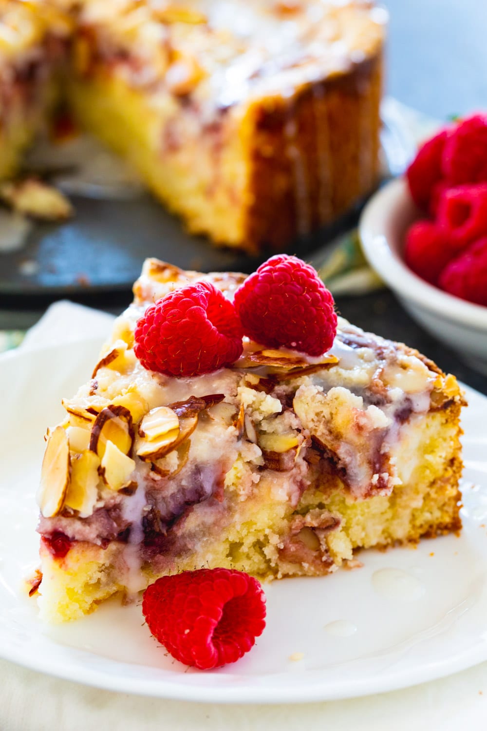 Slice of coffee cake topped with fresh raspberries.