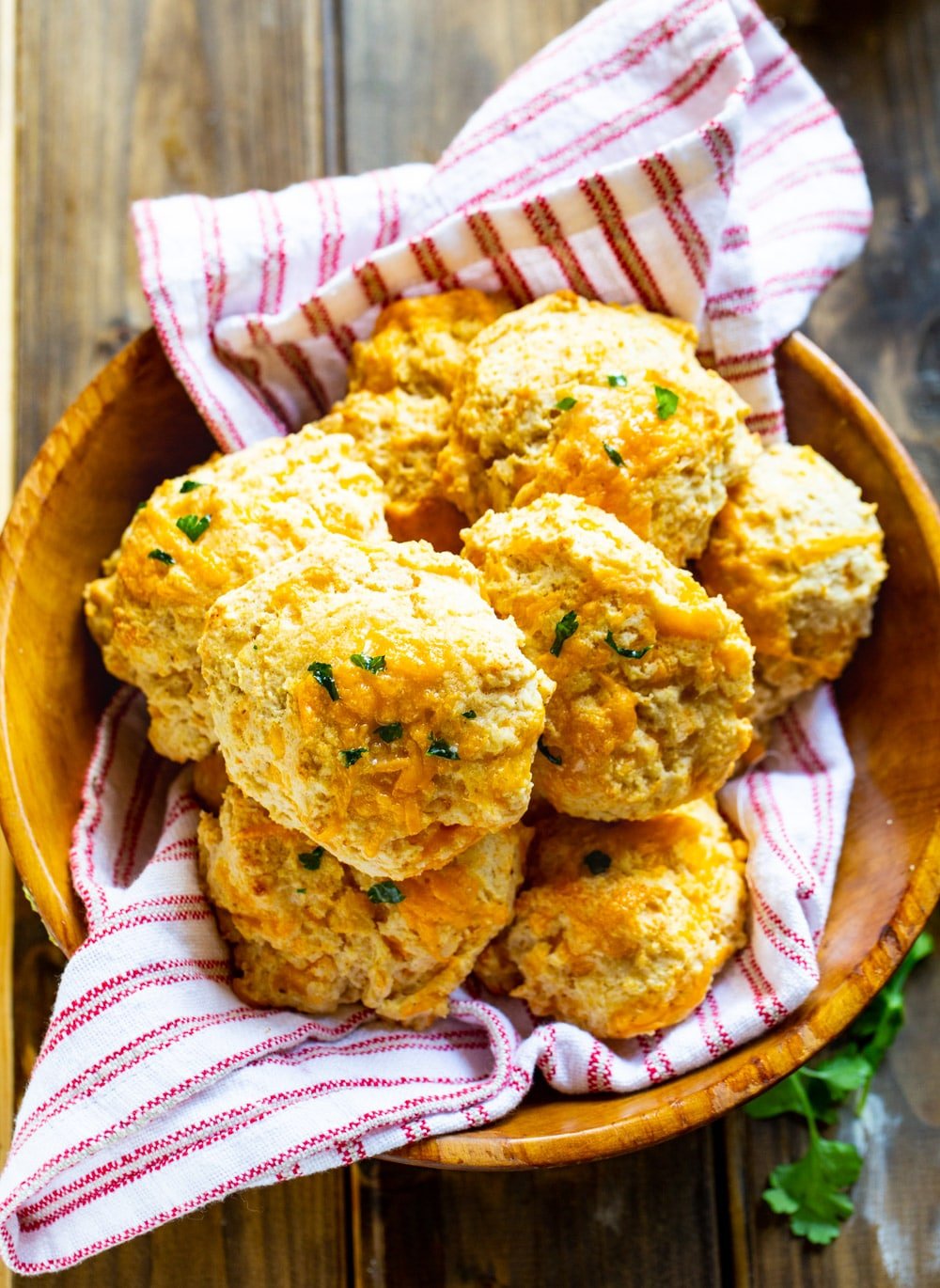 Overhead view of Cheddar Bay Biscuits in a wooden bowl with red and white cloth napkin.