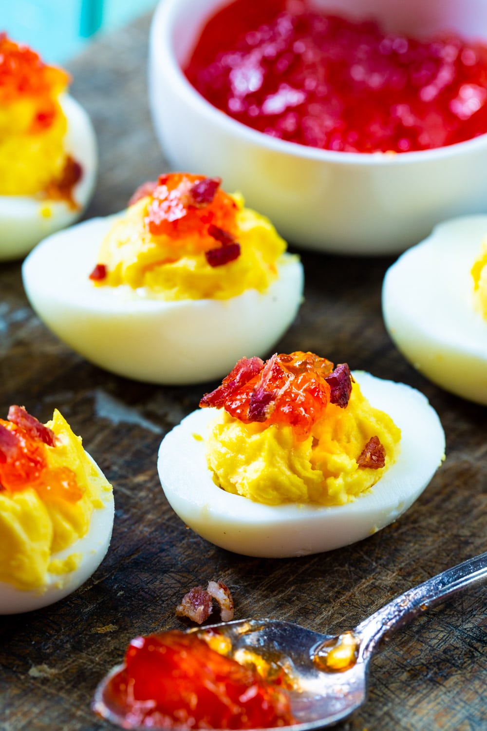 Red Pepper Jelly Deviled Eggs with Bacon with a bowl of pepper jelly.