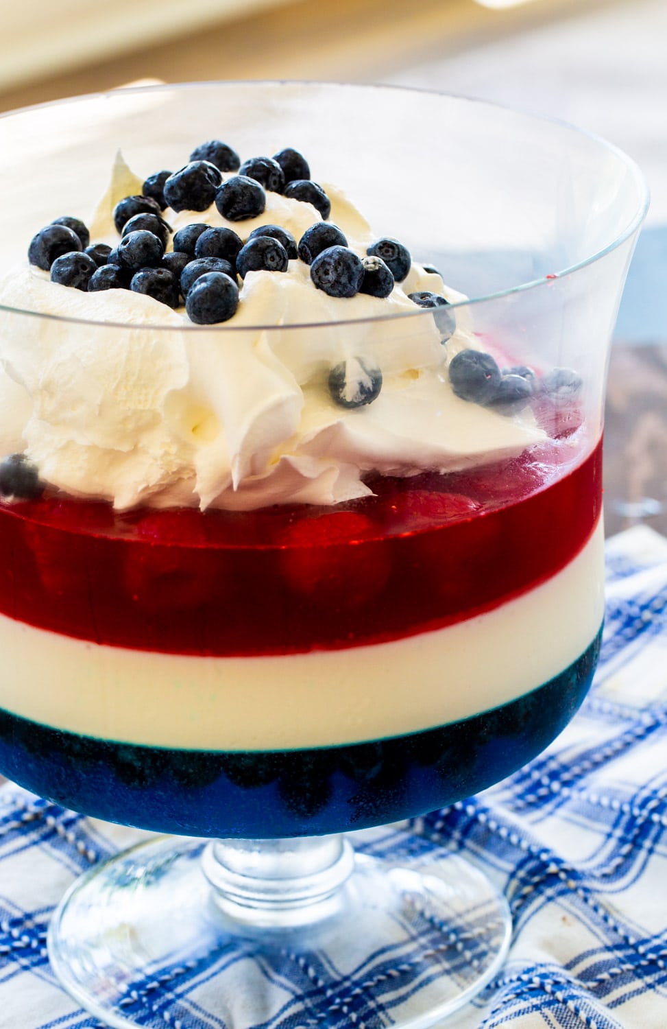 Red, White & Blue Jello Salad topped with whipped cream and blueberries.
