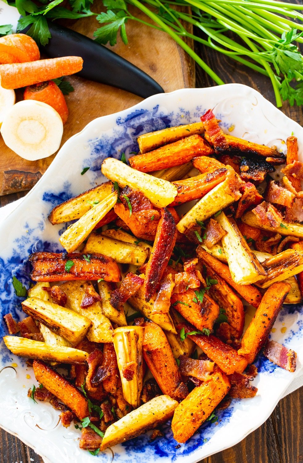 Roasted Carrots and Parsnips on platter with fresh carrots and parsnips next to it.