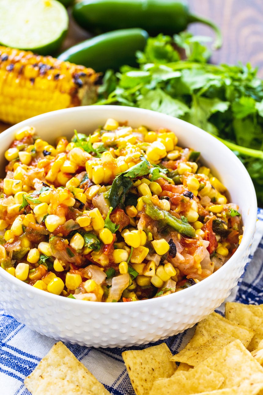 Roasted Corn Salsa in a white serving bowl with tortilla chips.