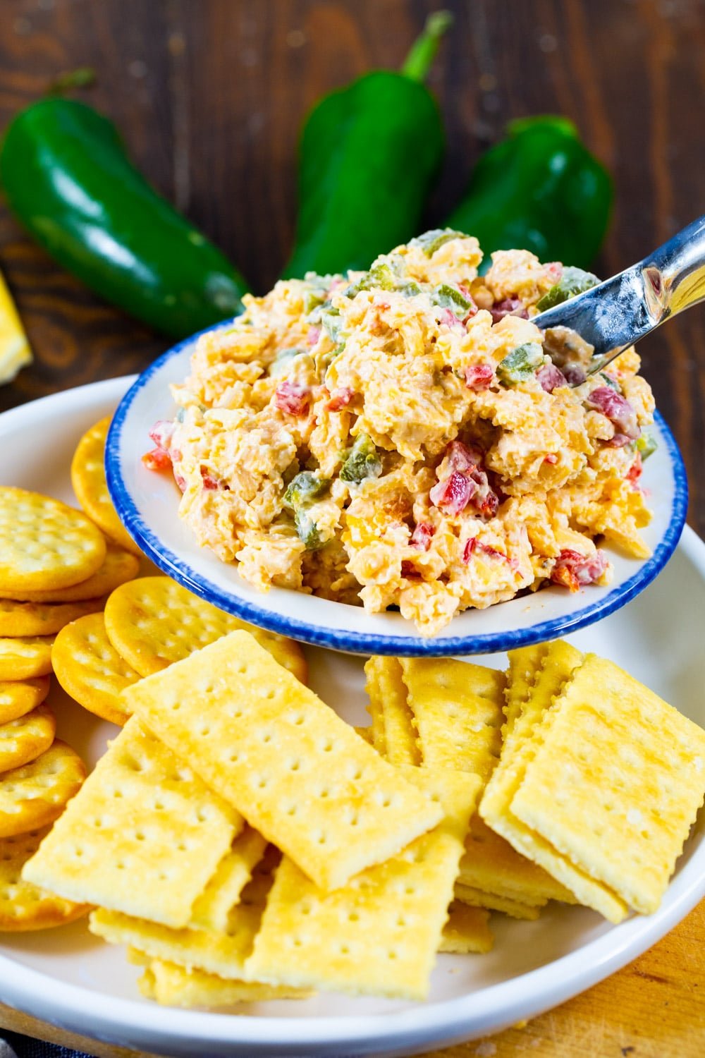 Pimento Cheese in a small bowl on a plate surrounded by crackers.