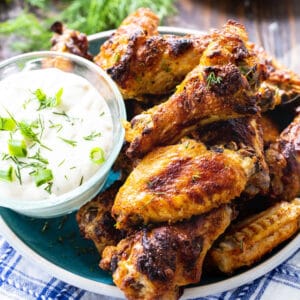 Wings arranged on plate with bowl of dipping sauce.
