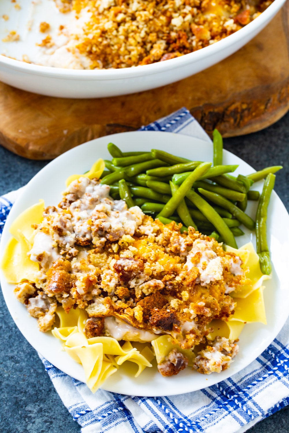 Sandy's Chicken over noodles on a plate with green beans.