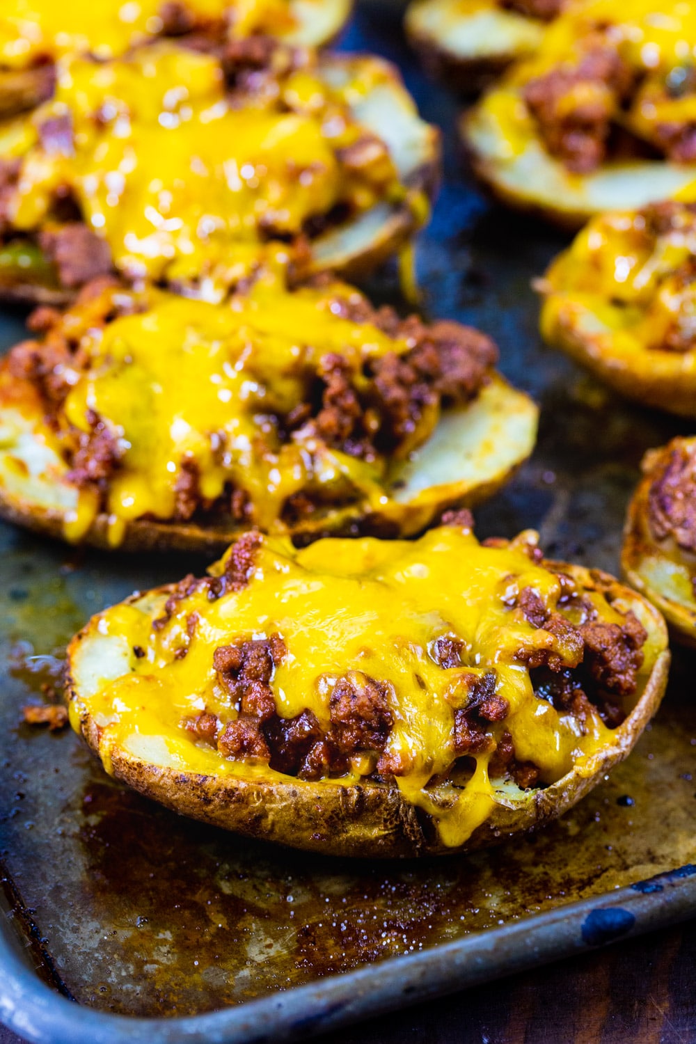 Potato Skins covered with cheese on a baking sheet.