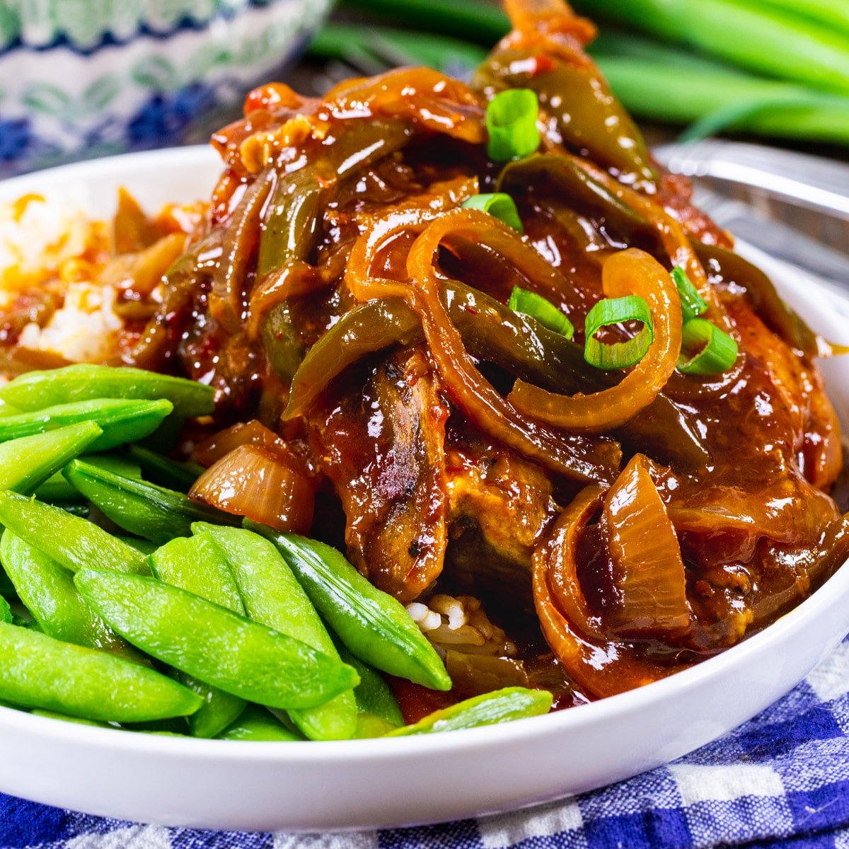 Slow Cooker Sweet and Tangy Pork Chops on a plate with sugar snap peas.
