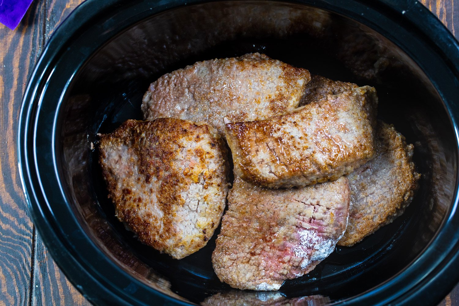 Browned pieces of cubed steak in slow cooker