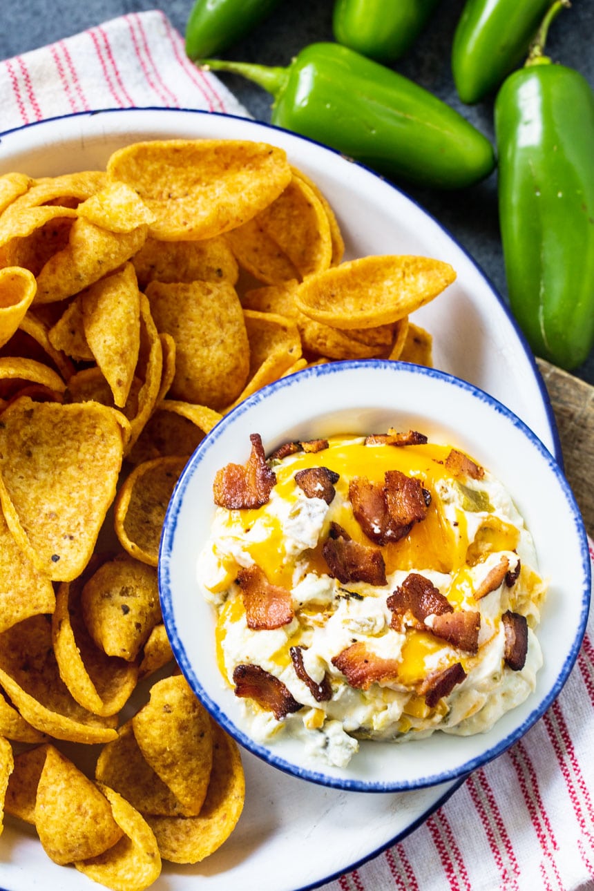 Dip in a bowl on a plate with corn chips.