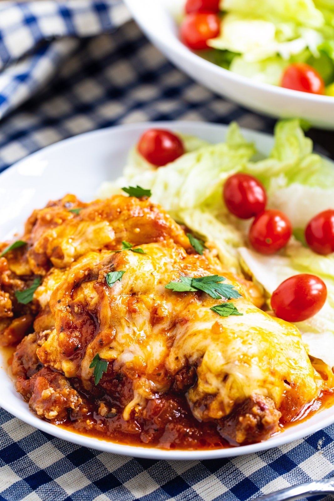 Serving of lasagna on a plate with salad.