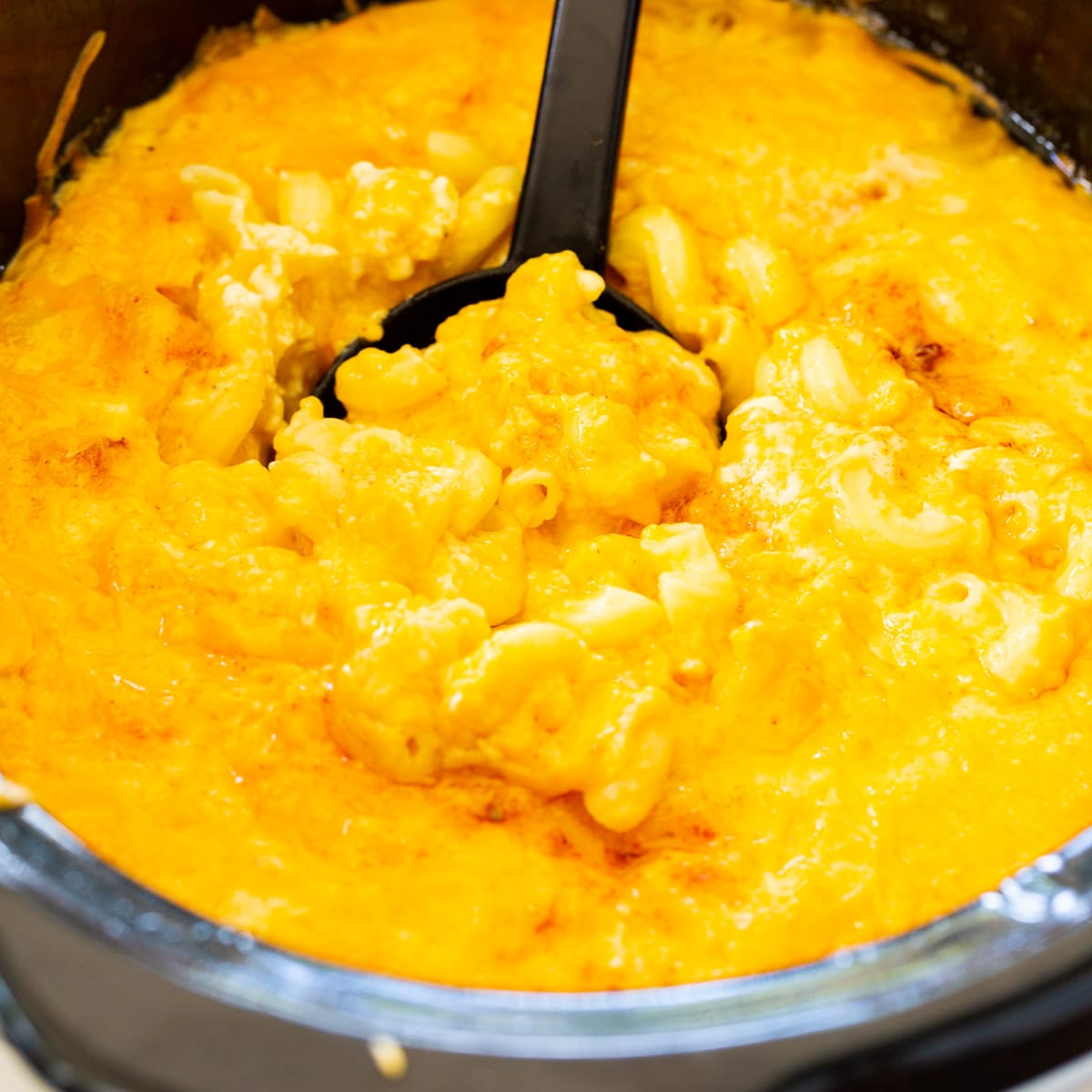 Spoon scooping Trisha Yearwood's Slow Cooker Mac and Cheese in a slow cooker.