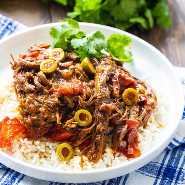 Slow Cooker Ropa Viejo over rice on a plate.