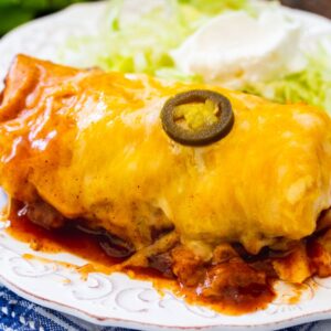 Slow Cooker Smothered Burrito on a plate with iceberg lettuce.