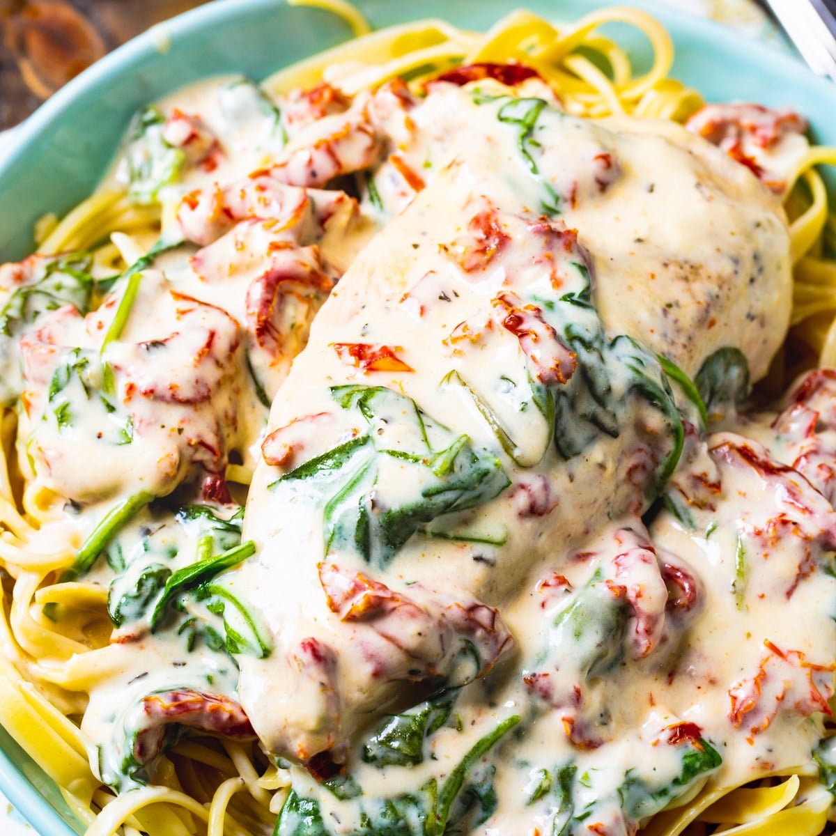 Slow Cooker Creamy Tuscan Chicken over pasta in a bowl.