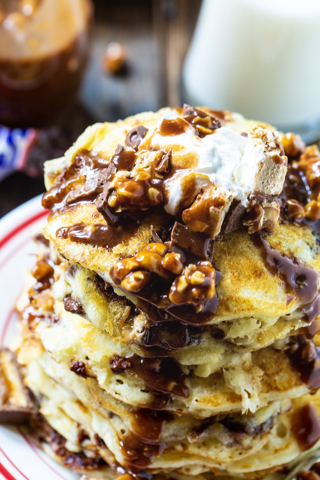 Stack of Snickers Pancakes topped with whipped cream.