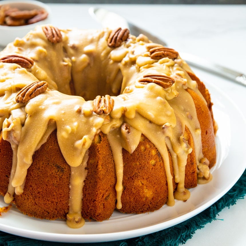 Bundt Cake covered with praline sauce on large white serving platter.