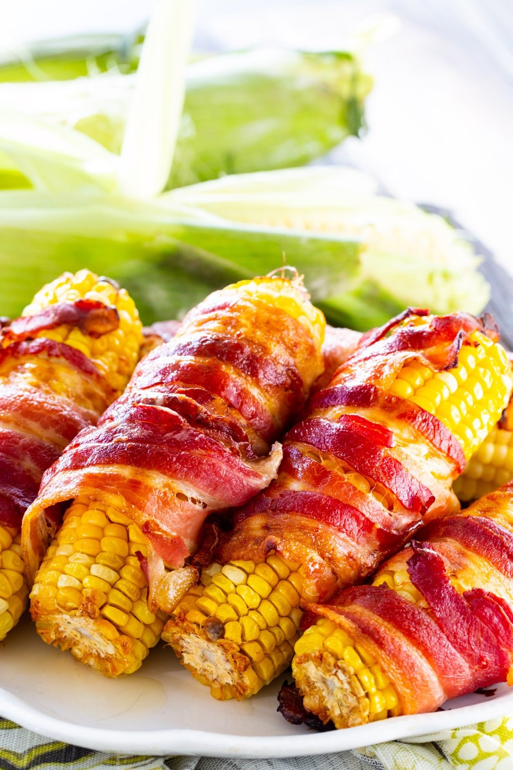 Corn wrapped in bacon on a serving platter.