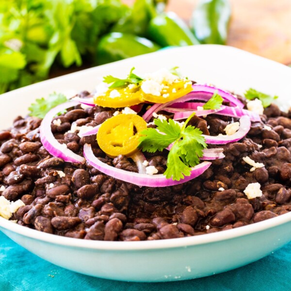 Spicy Black Beans in white bowl, topped with red onion and cilantro.